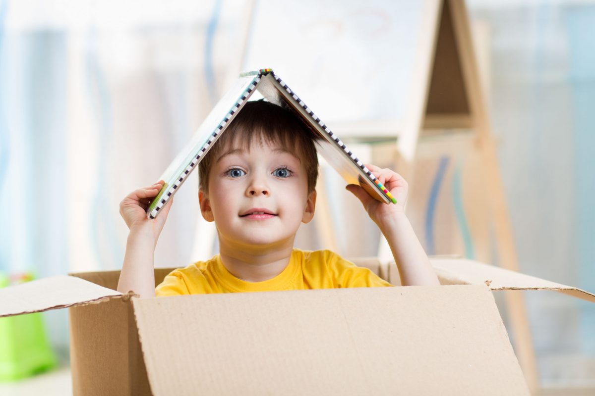 Boy popping head out of box with toy roof on head