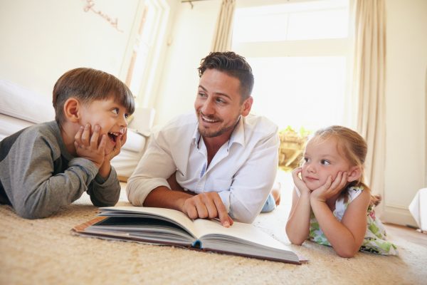 Happy young family lying on the floor reading a book