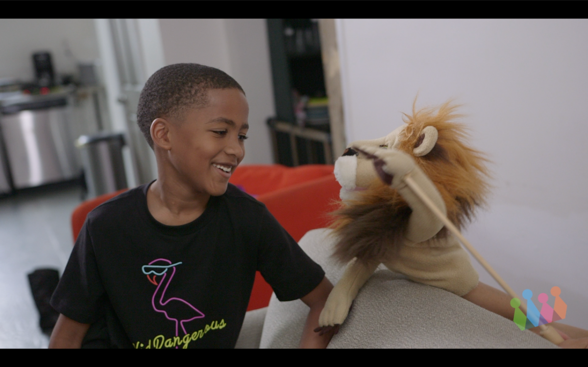 Boy smiling and sitting with lion puppet